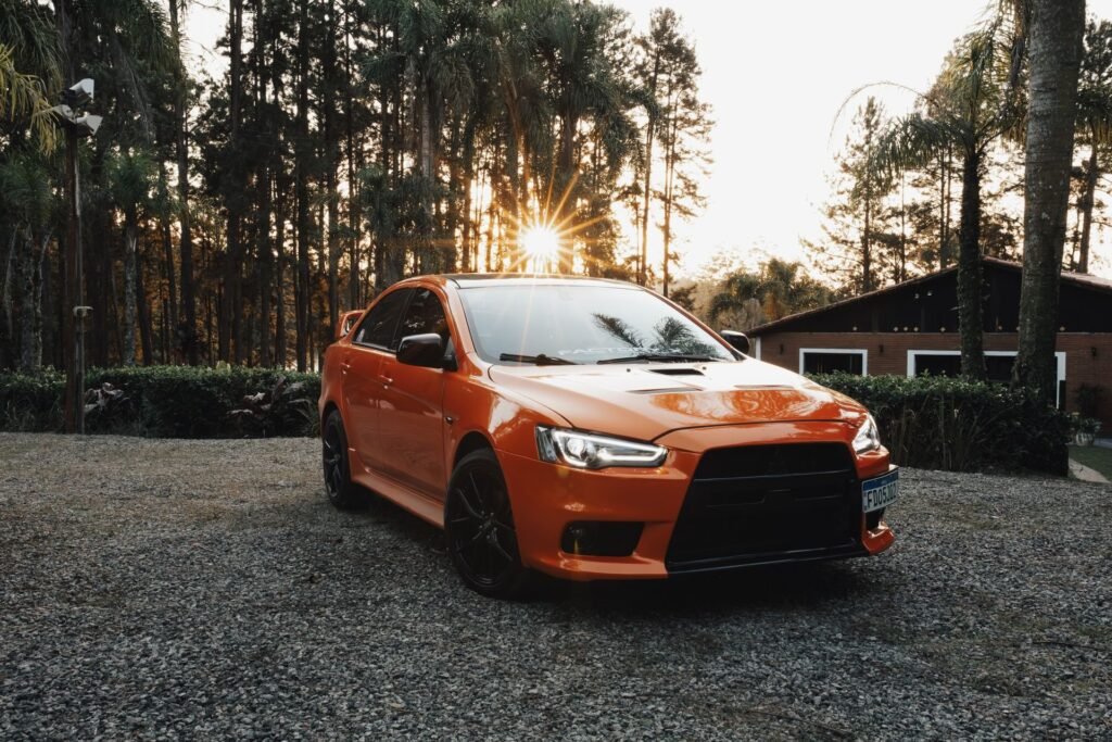Car on a gravel driveway by a house at sunset
