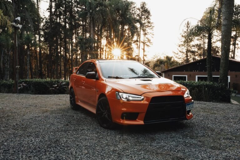 Car on a gravel driveway by a house at sunset