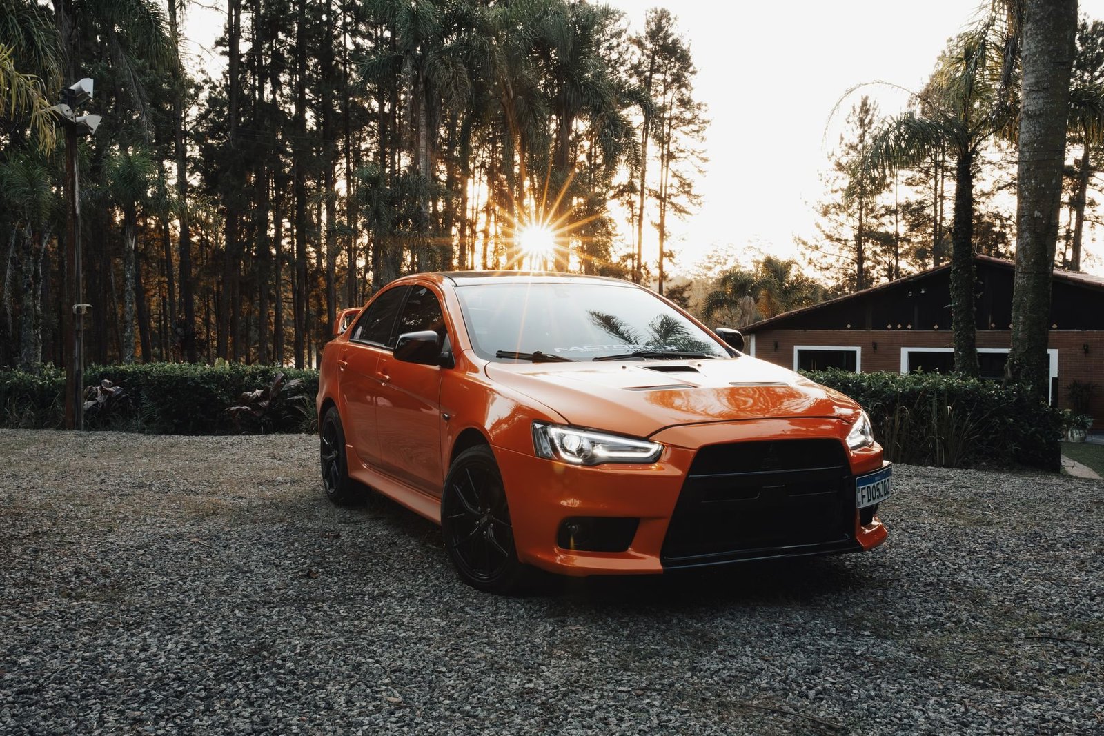 Car on a gravel driveway by a house at sunset