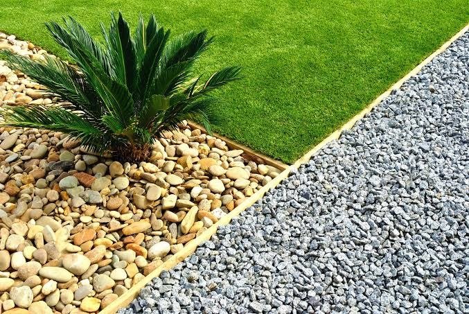 River rock and crushed gravel beds next to a green lawn